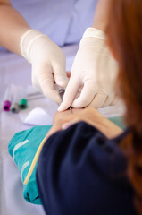 Close up nurse pricking needle syringe in the arm patient drawing blood sample for blood test , Health check