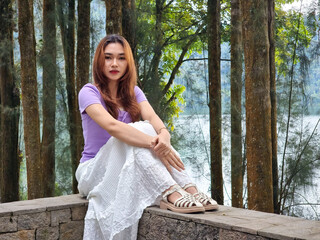 Beautiful Asian woman wearing a purple blouse and white skirt posing beautiful and sexy against the...