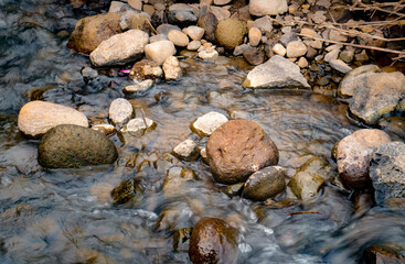 Obraz premium Small stones of various sizes are in the middle of the river flow