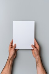 A person is holding a white piece of paper. The paper is blank and has no writing on it
