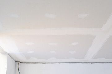 Interior building renovation shows gypsum board ceiling with smooth edges needing smooth plastering. Electrical wire near wall indicates construction of smooth ceilings