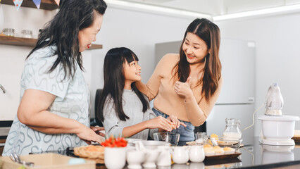 Grandmother cooking with daughter and mother family fun at home kitchen