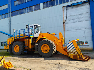 Heavy yellow wheel loader parked outside a large industrial building