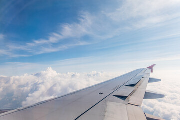Fototapeta na wymiar View from the airplane window at a beautiful cloudy sky and the airplane wing