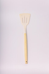 Kitchen White spatula on isolated white background. White silicone spatula with wooden handle. Cooking utensil used for cooking food in the kitchen of every house.this is the type with three holes