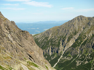 Mountain Valley View with Rocky Slope and Pine Shrubs under Clear Blue Sky