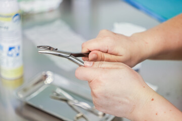 Close-up view of a medical worker's hands expertly handling stainless steel surgical pliers from a...