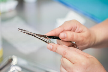A close-up view of hands holding sterile medical forceps, emphasizing the precise handling and...