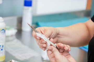 Close-up view of a medical professional's hands meticulously cleaning a specialized stainless steel...