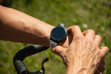 Athlete cyclist checking distance, pulse or fitness progress in apps after riding. Close up man...