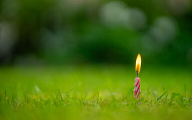 A burning candle stuck in the ground. A candle of memory.