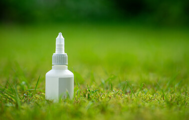A bottle of cyanoacrylate glue stands on the green grass. Super glue for instant bonding of plastic.
