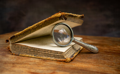 An open antique book with a magnifying glass for reading. Scientific literature.Read a book.