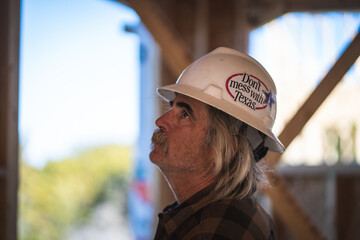 Construction Worker Wearing Hard Hat with Don't Mess with Texas Sticker Looking Up In Wooden Frame...
