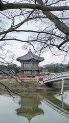 Naklejka premium Hyangwonjeong Pavilion at Gyeongbokgung Palace, Seoul, South Korea, on a cloudy day. This beautiful traditional Korean architecture is reflected in the pond, showcasing historical charm.