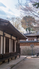 Naklejka premium A tranquil traditional Korean house at Bukchon Hanok Village in Seoul, South Korea. The photo captures the delicate wooden structure and tiled roof, surrounded by trees and peaceful courtyards.