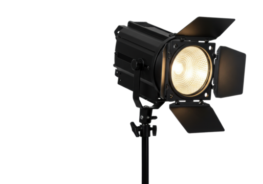 A black metallic studio Fresnel spotlight with open barn doors emitting bright warm white light on a black stand, isolated against a clean transparent studio background with copy space,