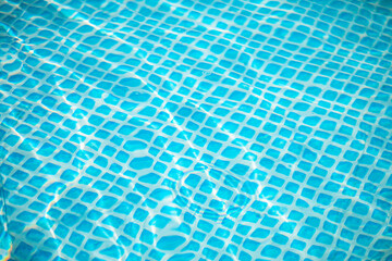Crystal-clear turquoise blue pool water surface is gently rippling, reflecting sunlight and...