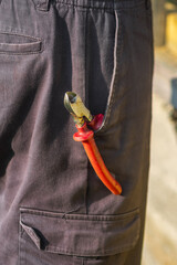 Close-up view of pruning shears nestled in the pocket of a gardener's cargo pants, providing easy access for maintaining vibrant plants and tending to flourishing gardens
