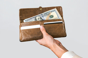 Hand Holding Open Brown Wallet with Hundred Dollar Bills
