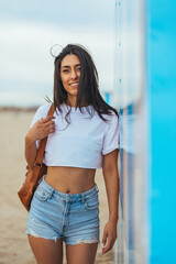Smiling Young Woman at the Beach Standing by a Vibrant Wall