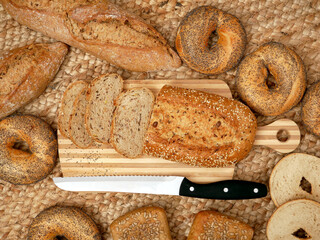 A variety of different types of bread, including sliced bread on a wooden cutting board with a...
