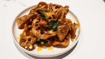close up of Singaporean style deep fried salt egg lotus roots chips with green peppers 