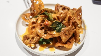close up of Singaporean style deep fried salt egg lotus roots chips with green peppers 