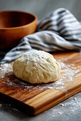 Fresh floured dough on wooden board with striped cloth in kitchen