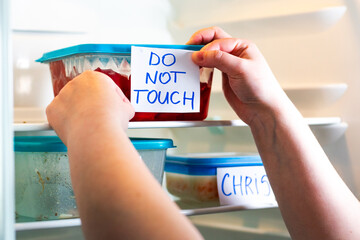 Office fridge with angry Do Not Touch My Food stickers on meal containers. Workplace humor,...