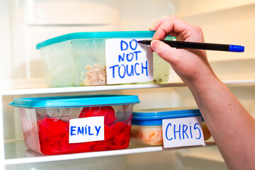 Do Not Touch sticker on lunch boxes in office refrigerator. Angry and hungry workers concept.