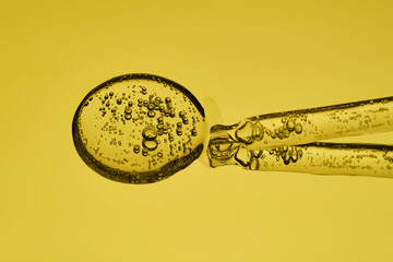 A serum pipette with bubbles on a yellow background.