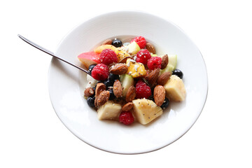 A wholesome breakfast bowl filled with fresh fruits like raspberries, blueberries, pineapple, apple, paired with almonds, chia seeds, and natural yoghurt. Captured from above in natural light
