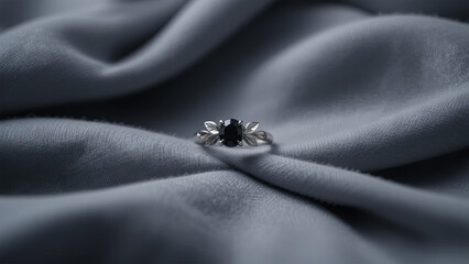 Elegant silver ring with a black oval gemstone and leaf design on soft grey fabric