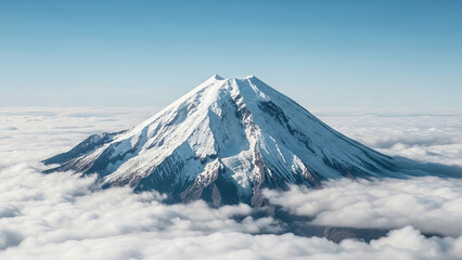 Majestic snow capped volcano peak emerges from a blanket of clouds under a clear blue sky