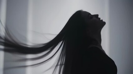 Elegant hair flip silhouette in slow motion against soft light background
