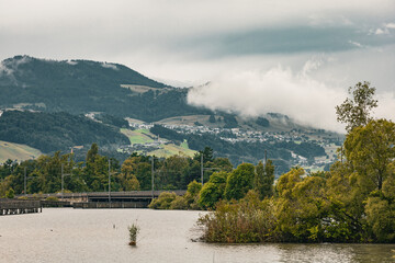Picturesque landscape of Swiss countryside with forested hills, a lake in the foreground, and a...