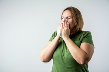 Sick woman blowing nose into tissue and suffering from cold or allergy symptoms, health issue,...