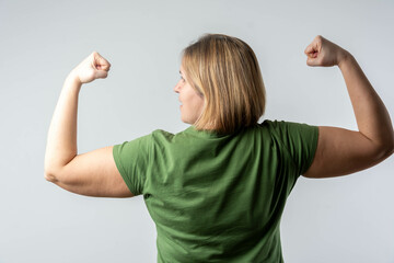 Strong confident woman flexing biceps from behind, showing physical power and determination, girl...