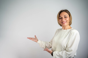 Confident beautiful businesswoman pointing with both hands at copy space, advertising concept,...
