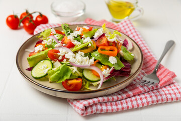 Cucumber salad on a wooden background.Homemade salad with fresh vegetables, cucumber, tomato, sweet pepper and lettuce in a plate.Vegetarian spring salad.Vegetarian diet.Healthy eating.Space for text