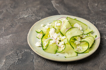 Cucumber salad on a wooden background.Homemade salad with fresh vegetables, cucumber, tomato, sweet pepper and lettuce in a plate.Vegetarian spring salad.Vegetarian diet.Healthy eating.Space for text