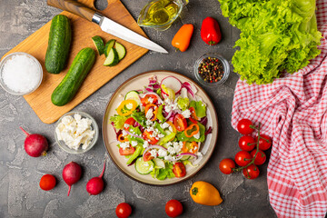 Cucumber salad on a wooden background.Homemade salad with fresh vegetables, cucumber, tomato, sweet pepper and lettuce in a plate.Vegetarian spring salad.Vegetarian diet.Healthy eating.Space for text
