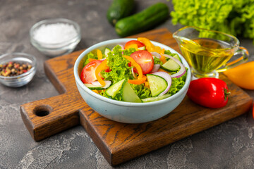 Cucumber salad on a wooden background.Homemade salad with fresh vegetables, cucumber, tomato, sweet...