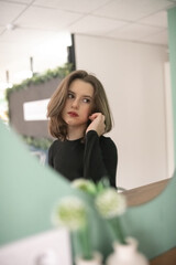 Portrait of a young beautiful long-haired girl in dark clothes in an interior studio.