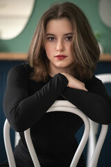 Portrait of a young beautiful long-haired girl in dark clothes in an interior studio.