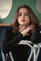 Portrait of a young beautiful long-haired girl in dark clothes in an interior studio.
