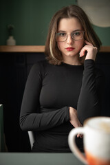 Portrait of a young beautiful long-haired girl in dark clothes in an interior studio.