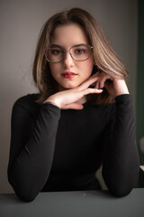 Portrait of a young beautiful long-haired girl in dark clothes in an interior studio.