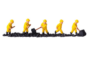 Miniature construction workers in yellow uniforms performing excavation on black soil in a playful and creative layout